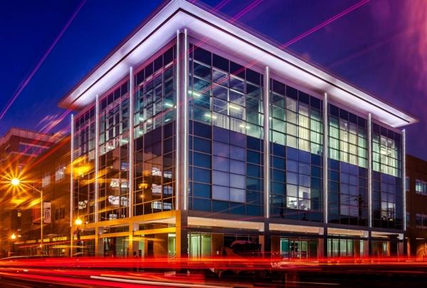 Exterior photo of Maryland Proton Treatment Center at night. Vehicle taillights create red streaks in time lapse image.